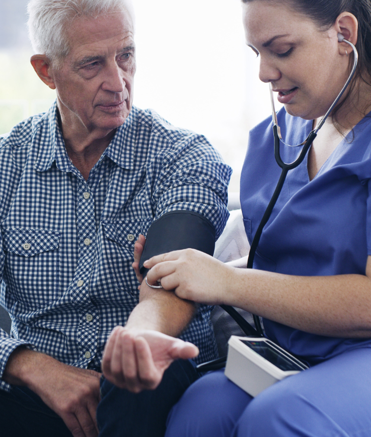 Female nurse taking an older man's blood pressure