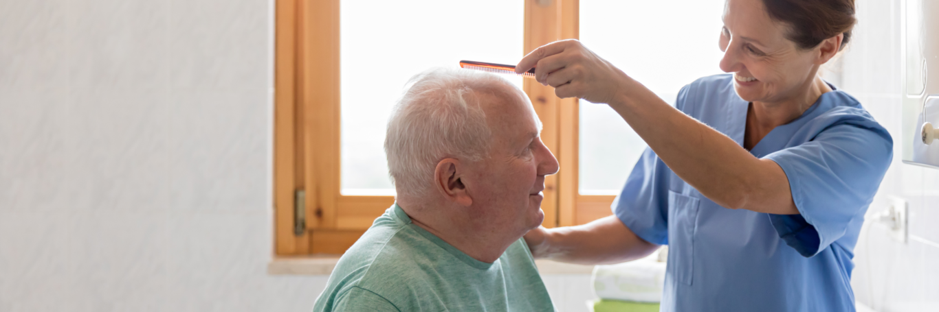 Female nurse combing older man's hair